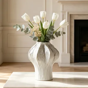 Detail view of a white minimalist ceramic vase with organic texture and tulips