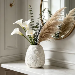 Detailed view of an embossed white ceramic vase with elegant floral patterns in a home setting