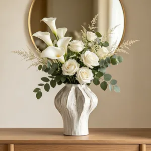 Macro detail of minimalist fluted white ceramic vase with fresh rose and lily arrangement