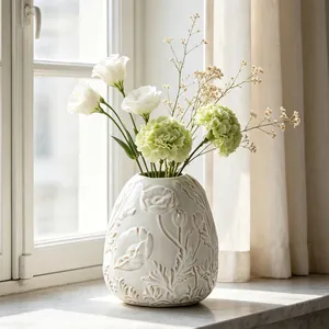 Vintage cream relief ceramic vase featuring elegant floral patterns under soft natural light