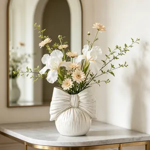 Detailed view of cream ceramic vase featuring an elegant bow knot design and floral arrangement