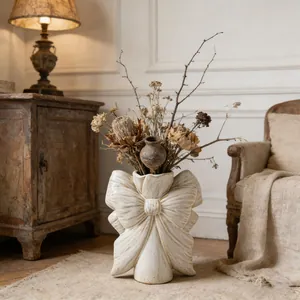 Vase nœud en céramique blanche vintage avec fleurs séchées dans une pièce cosy