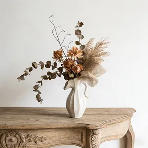 Noordse keramische vaas in crème-stijl met droogbloemen op vintage houten tafel
