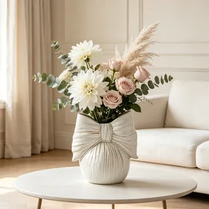 Elegant bow-shaped white ceramic vase with floral arrangement on a minimalist coffee table