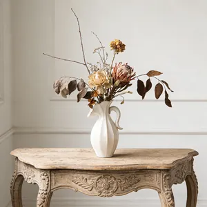Vintage crème keramische vaas met handvat en geribbelde textuur voor droogbloemen.