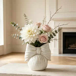 Elegant cream ceramic bow-shaped vase with fresh floral arrangement in a living room