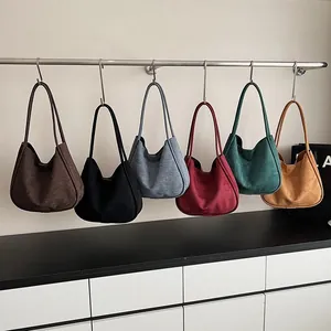 Grands sacs fourre-tout en daim de plusieurs couleurs suspendus sur un présentoir