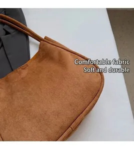 Vue macro détaillée de la texture d'un grand sac bandoulière en daim marron doux.