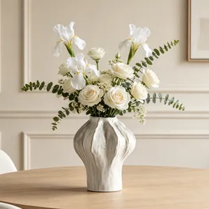 Detailed view of a minimalist white textured ceramic vase with fresh white roses.