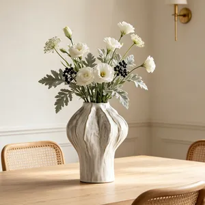 Macro view of a textured white ceramic vase with white flowers on a wooden table