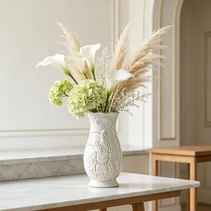 Elegant white relief ceramic vase with calla lilies and pampas grass on marble table