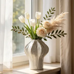 Detail of a white ceramic vase with ribbed texture and fresh flower arrangement on windowsill.