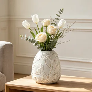 Detailed macro view of a white cream ceramic vase featuring elegant floral embossed texture