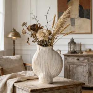 Rustikale Keramikvase mit Trockenblumen auf einem antiken Holztisch