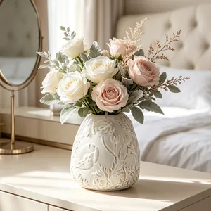 Detailed view of cream-white ceramic vase with embossed floral pattern on a table
