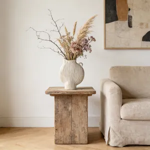 Minimalistische unglasierte Keramikvase auf einem rustikalen Holzhocker im Raum