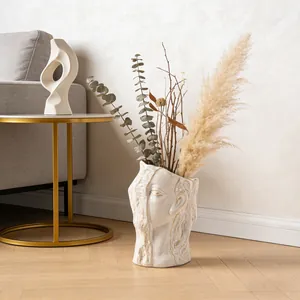 Abstract human face ceramic vase with dried pampas grass in a modern cozy living room