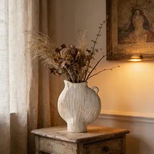Detailansicht einer strukturierten Keramikvase mit Trockenblumen in warmem Interieur-Stil