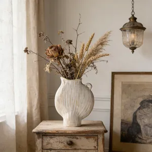 Künstlerische Keramikvase mit gerippter Struktur und Trockenblumen auf einem Holztisch