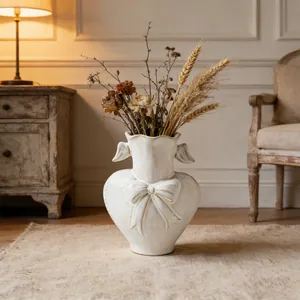 Rustic white heart-shaped ceramic vase with bow detail in a vintage room setting