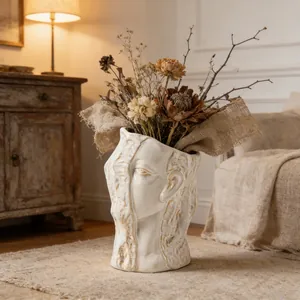 Close-up of abstract human face ceramic vase with dried flowers in warm room setting