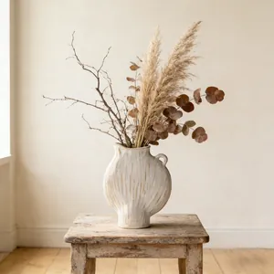 Detailansicht einer minimalistischen cremefarbenen Keramikvase auf einem rustikalen Holzhocker