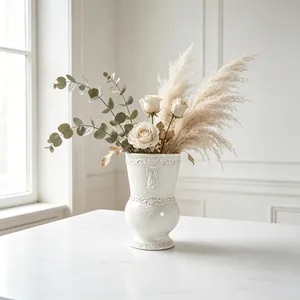 Detail of a vintage white ceramic vase with rabbit relief and dried floral arrangement.