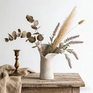Primo piano di un vaso in ceramica color crema con motivi floreali a rilievo e bordo