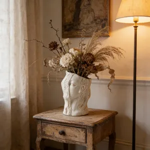 Artistic abstract human face ceramic vase with dried flowers on a vintage table