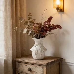 Vaso per fiori minimalista in ceramica bianca con rilievo su mobile rustico in legno