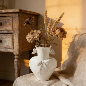 Artistic ceramic heart vase with bow detail and wing handles in a warm sunlit room