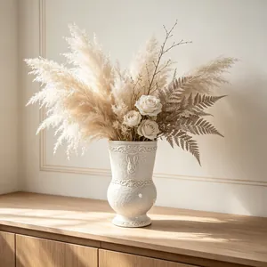 Elegant white embossed ceramic vase with pampas grass and white roses in sunlight