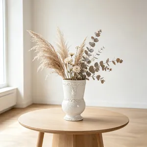 French vintage white ceramic vase with relief detail on a wooden table with pampas grass