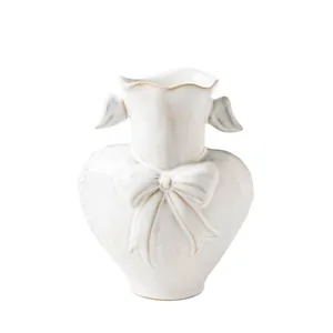 Modern white ceramic heart-shaped vase with bow and wing accents for home decor