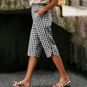 Side view of gingham cropped pants showing curved hem slit and button decoration