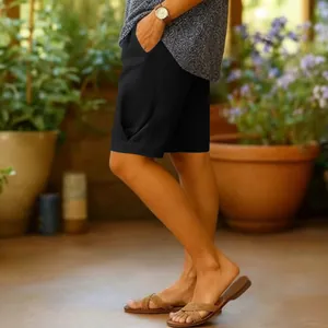 Détail d'un short large en coton et lin noir pour femme dans un cadre de jardin ensoleillé