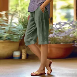 Vue latérale d'un short ample en coton et lin vert olive pour femme avec poches au jardin.