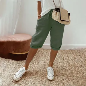 Casual green cotton linen cropped pants for women styled with white sneakers and woven bag