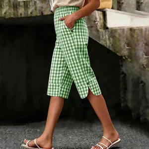 Side view of green and white gingham capri pants featuring button detail and slit hem