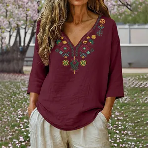 Close-up of retro ethnic embroidery on a burgundy cotton linen V-neck blouse