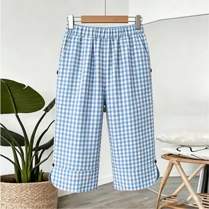 Detail view of women's blue and white gingham cropped pants presented in a home setting