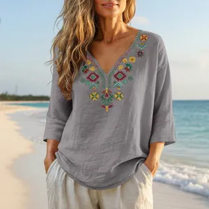 Detail view of boho grey cotton linen blouse with colorful floral embroidery on V-neck