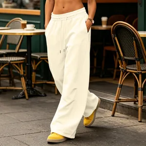 Cream wide-leg drawstring sweatpants styled with yellow sneakers at outdoor cafe.
