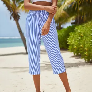 Detail of blue and white striped cropped pants with drawstring waist on a tropical beach