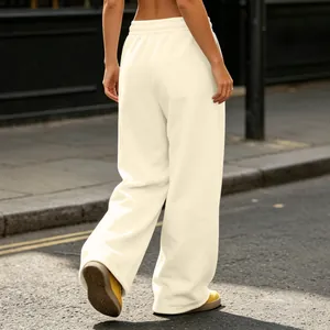 Back view of cream wide-leg baggy sweatpants with soft drape in an urban street setting