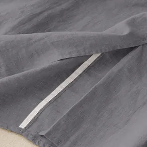 Close-up of grey cotton-linen fabric texture and slit hem detail on a midi skirt.