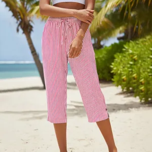Close-up detail of red and white striped drawstring capri pants in a beach setting