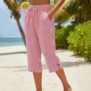 Detailed view of red and white striped cropped pants on a tropical beach setting