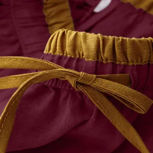 Macro detail of high-waist vintage cotton linen skirt showing burgundy fabric and yellow tie