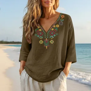 Detail view of retro embroidered cotton linen V-neck blouse for women in a beach setting